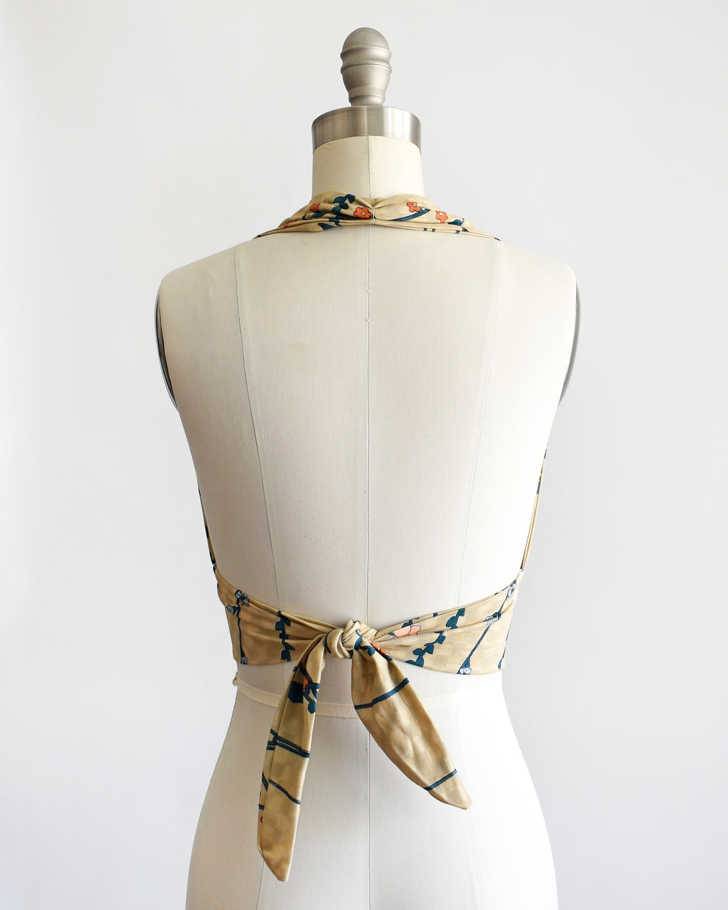 back view of a vintage 1970s floral halter top on a dress form