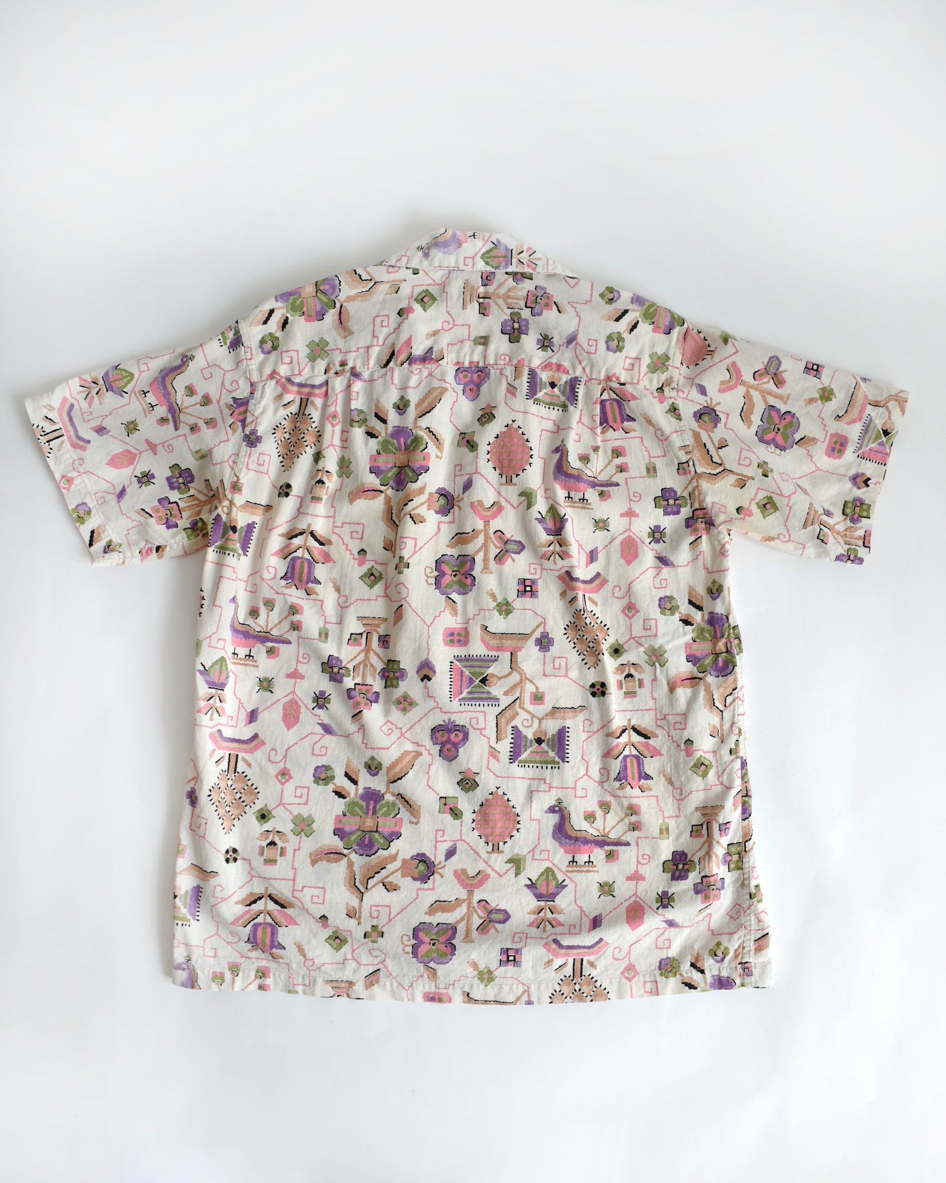 back view of a vintage 1950s Tiana Pittelle short-sleeve Hawaiian aloha shirt with a colorful pattern on a white background