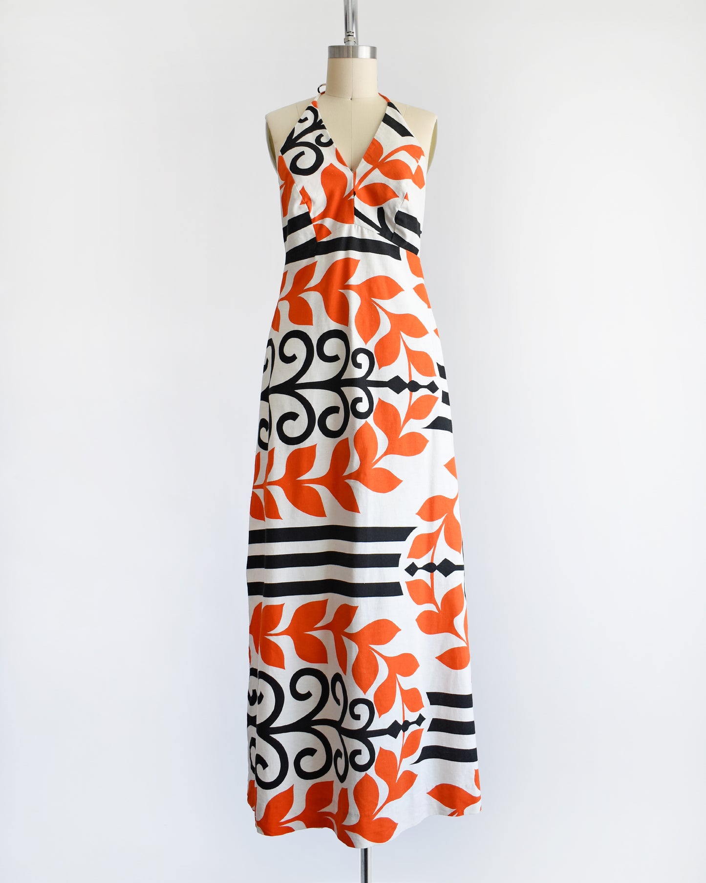 a vintage 1970s Baba Kea Hawaiian white halter dress that has a bold orange and black print