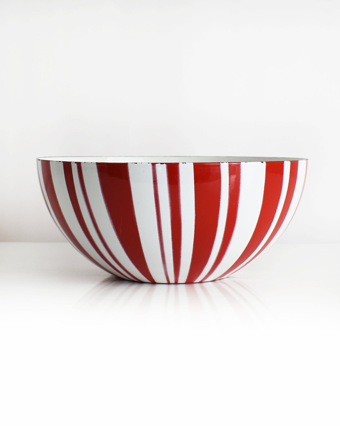 a vintage red and white striped Cathrineholm bowl on a white background