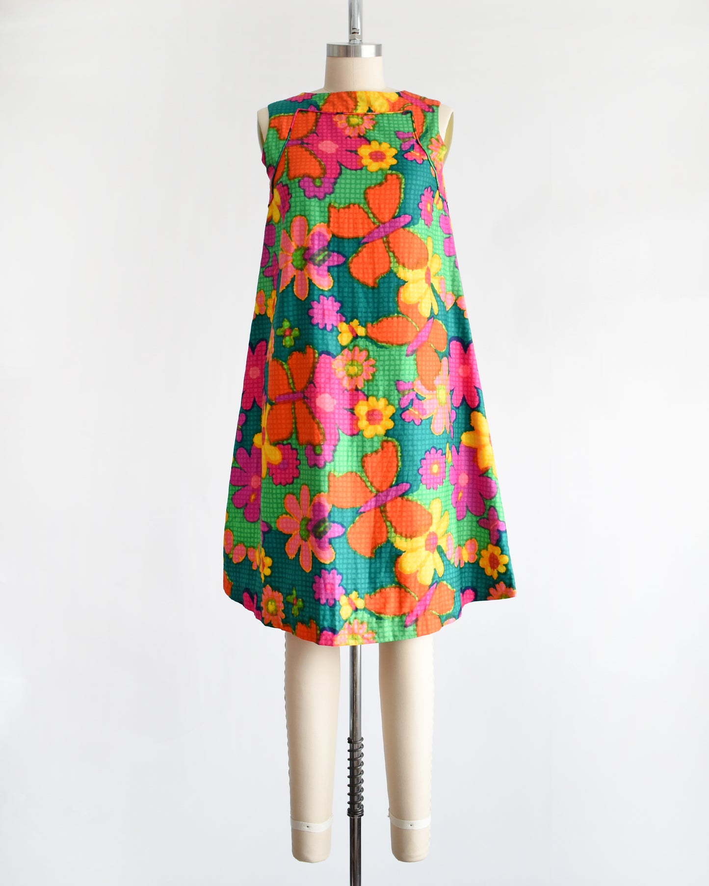 a vintage 1960s colorful floral dress on a mannequin against a white background