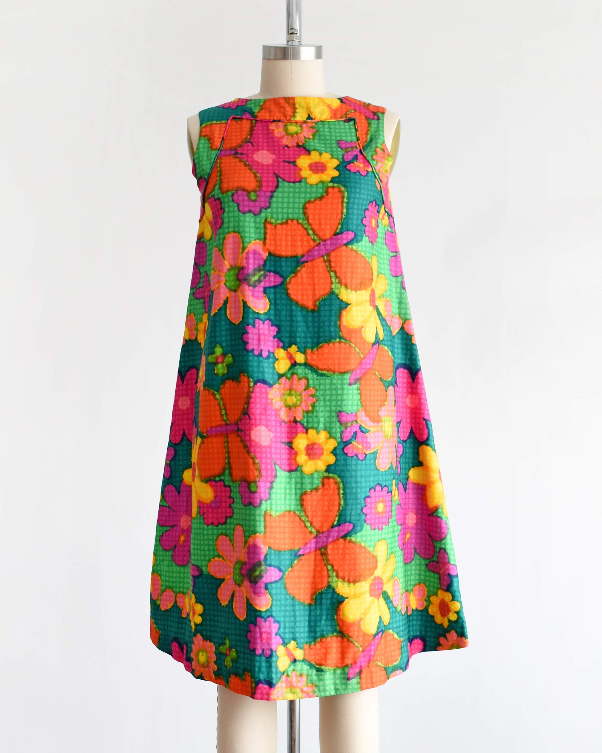 a vintage 1960s colorful floral dress on a mannequin against a white background