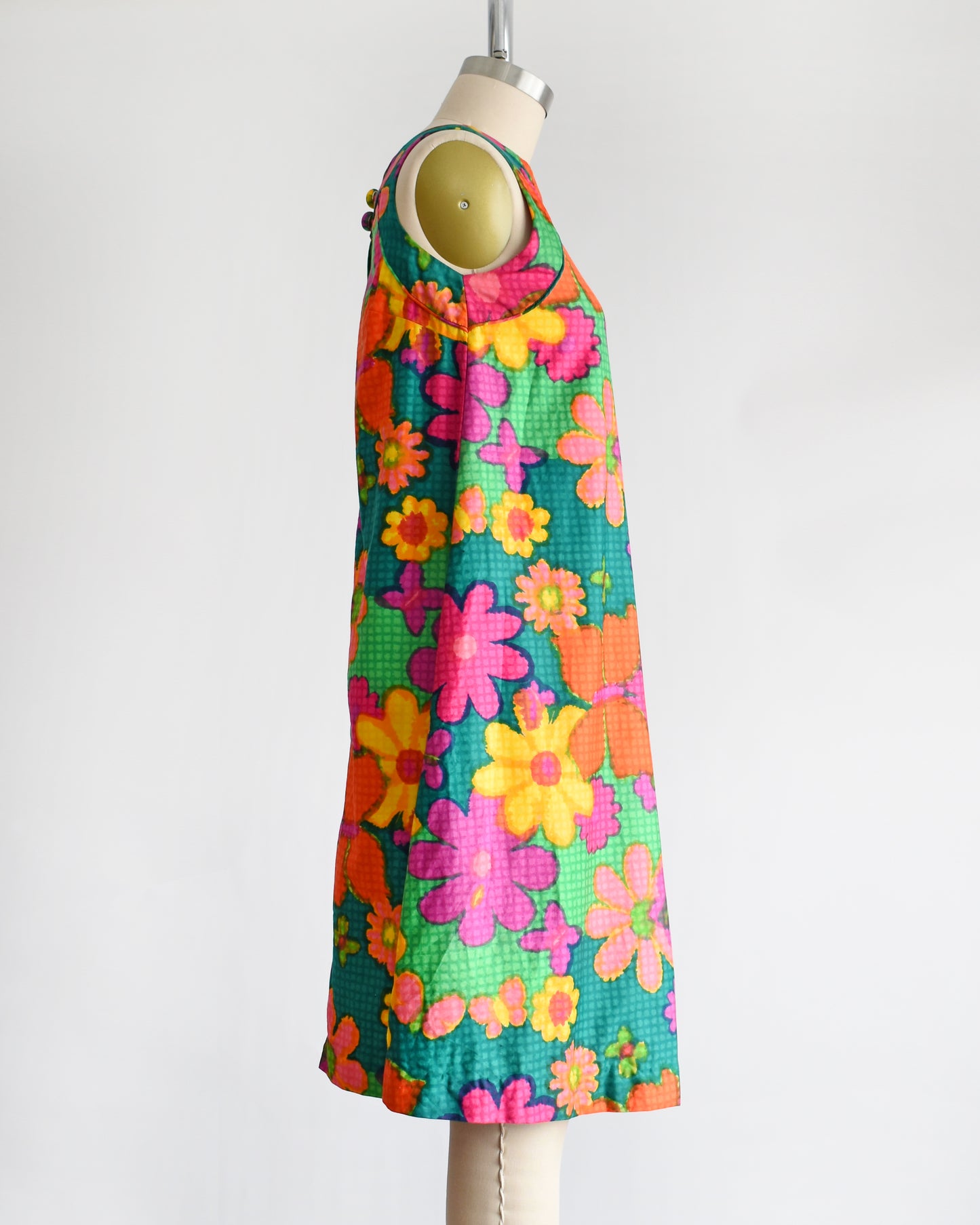 side view of a vintage 1960s colorful floral dress on a mannequin against a white background