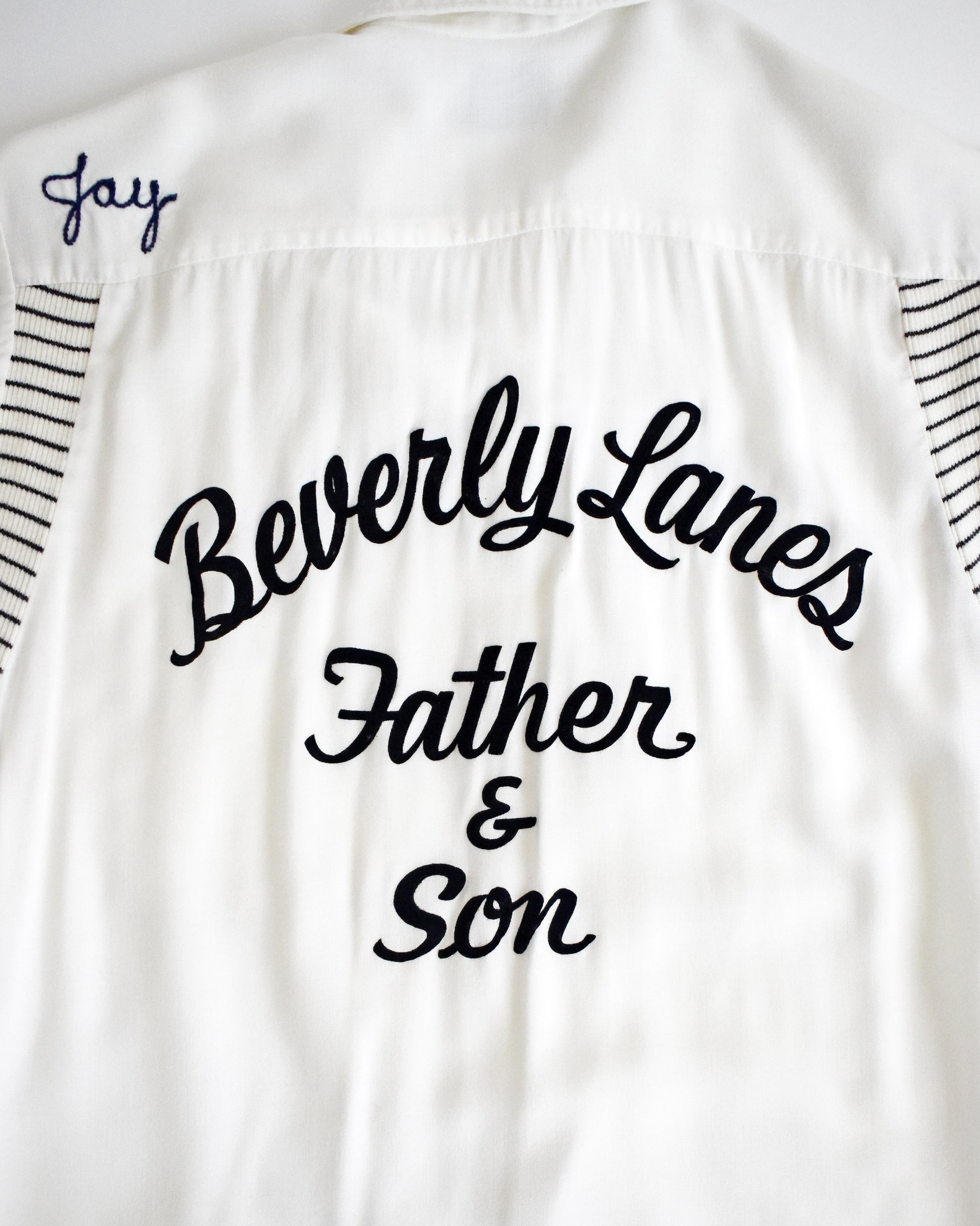 close up of the back of a vintage 1950s Olympian bowling white shirt with 'Beverly Lanes Father & Son' text on a white background