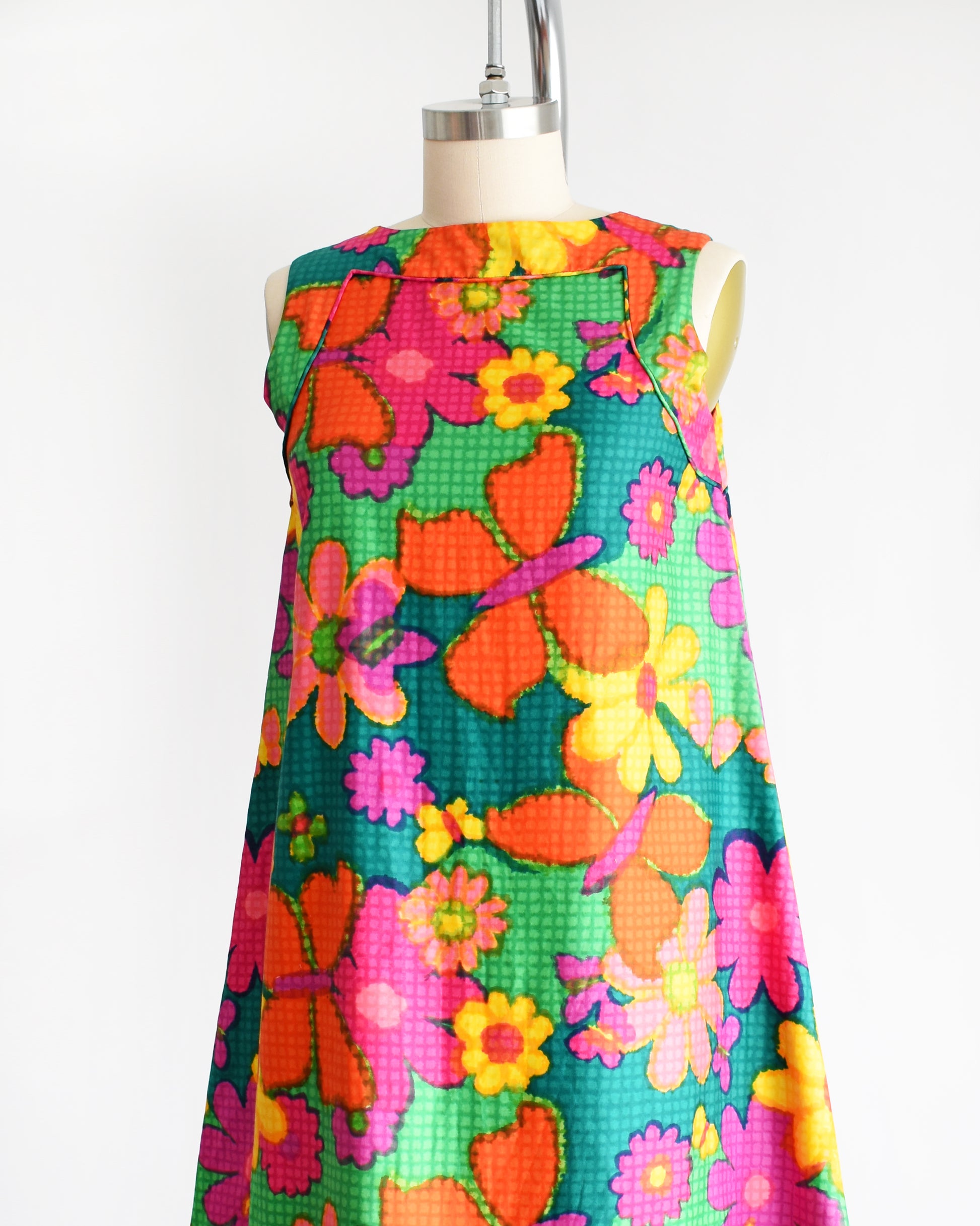 side front view of a vintage 1960s colorful floral dress on a mannequin against a white background