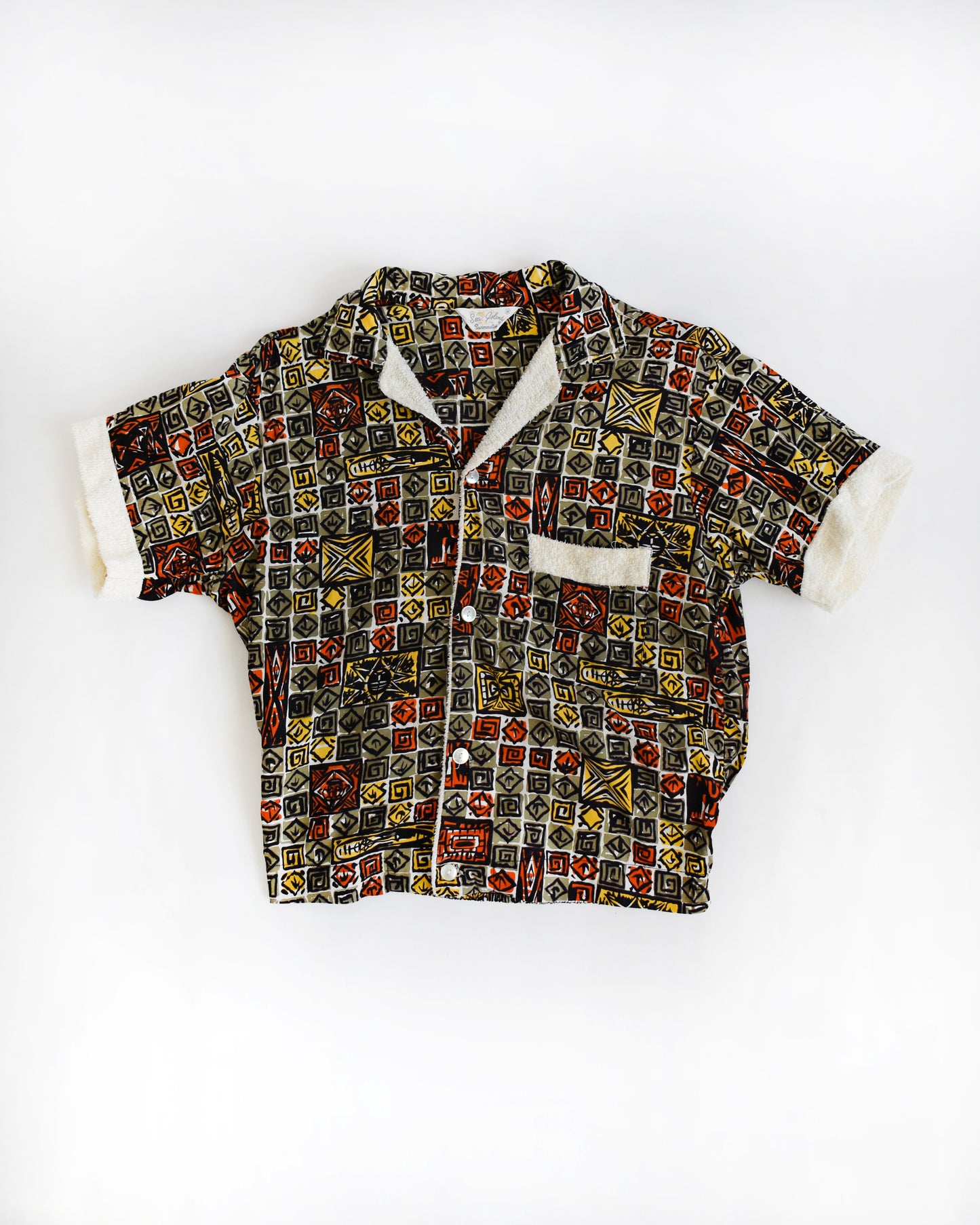 a vintage 1960s short-sleeve cabana shirt with geometric pattern on a white background