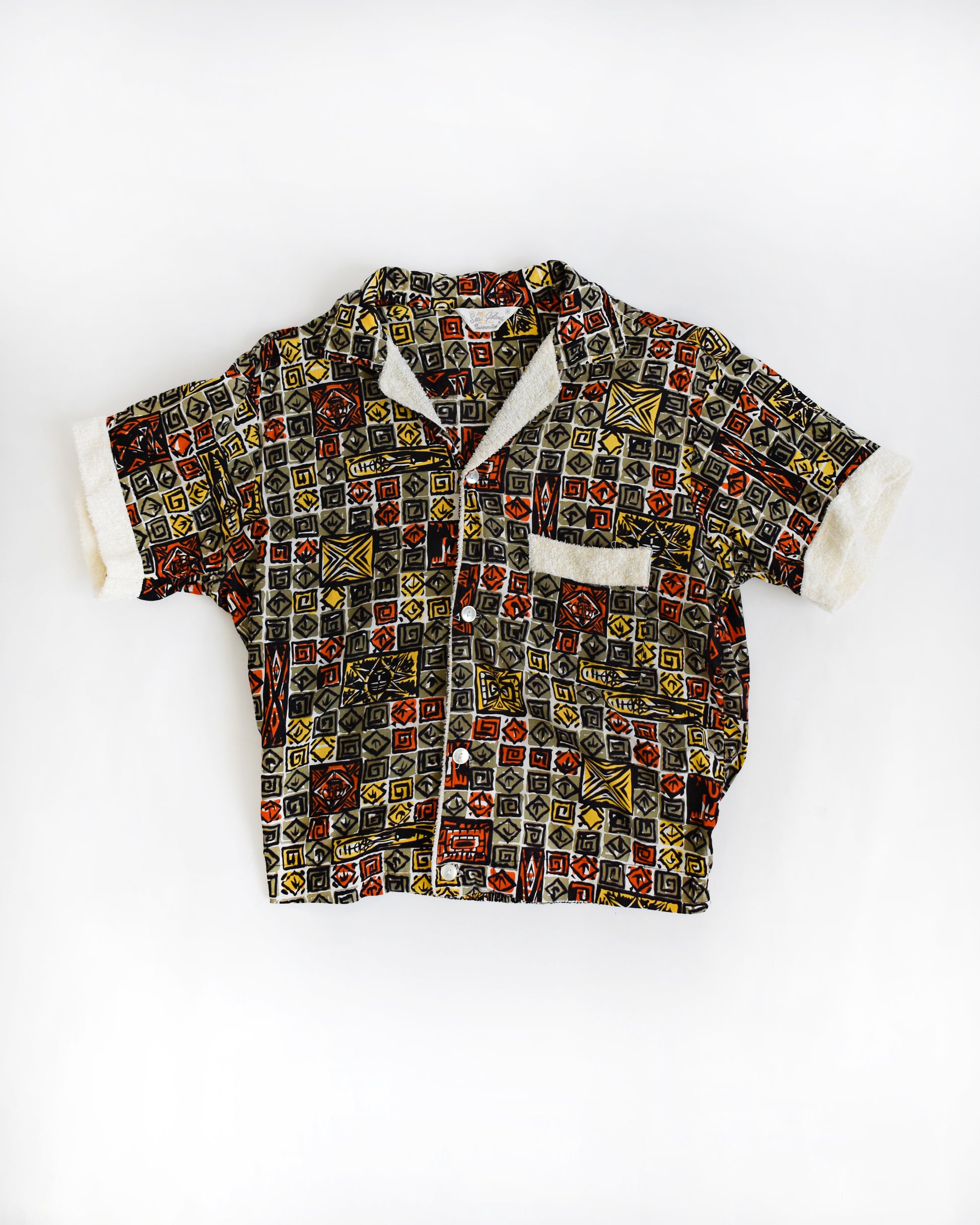 a vintage 1960s short-sleeve cabana shirt with geometric pattern on a white background