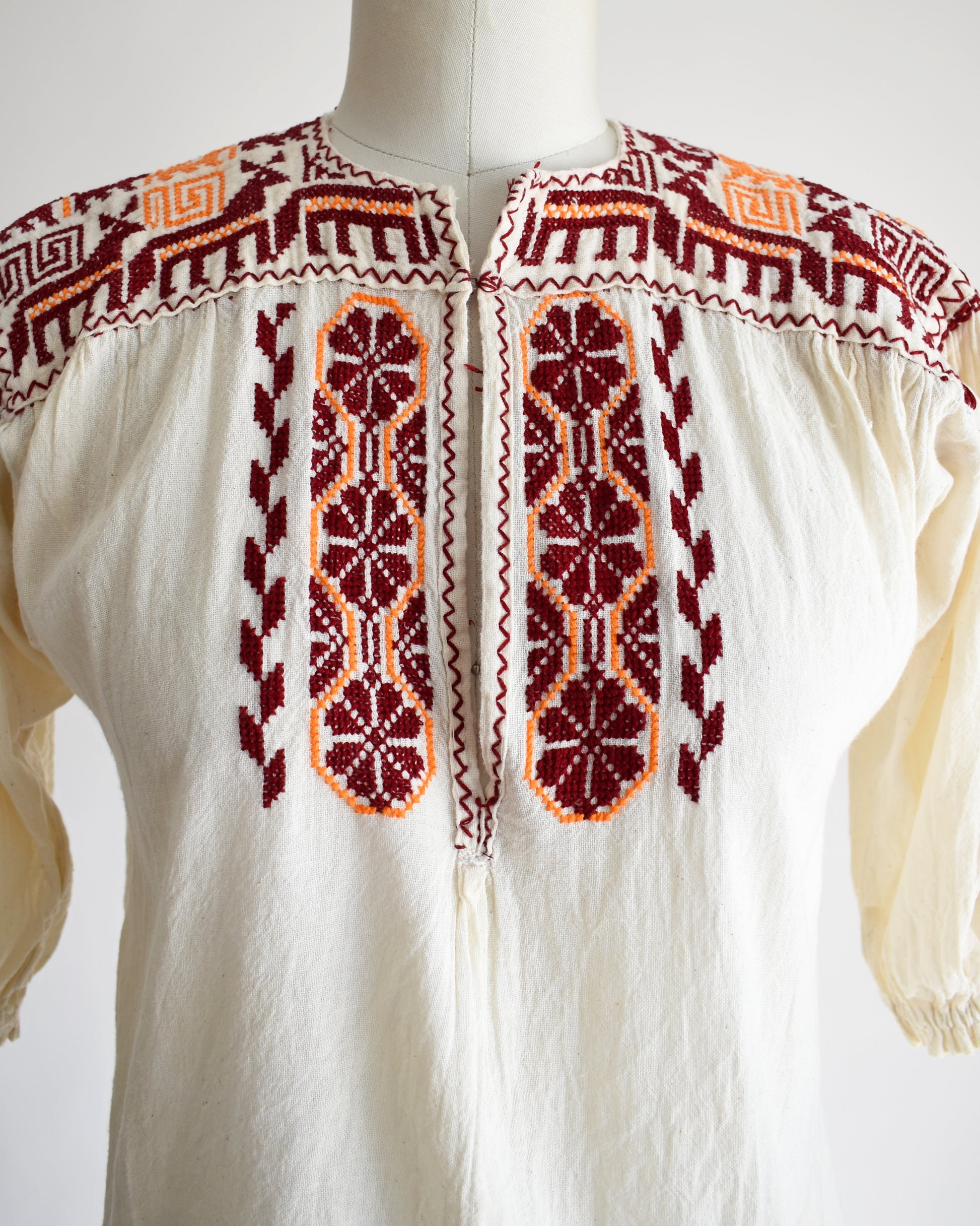 Close up of the burgundy and orange embroidered floral and what looks like llamas motif across the shoulders and down the front.