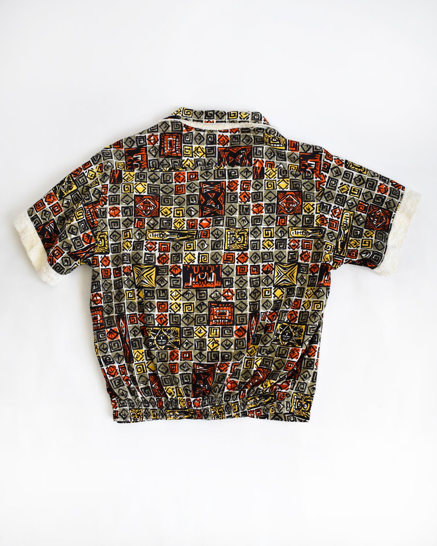 back of a vintage 1960s short-sleeve cabana shirt with geometric pattern on a white background