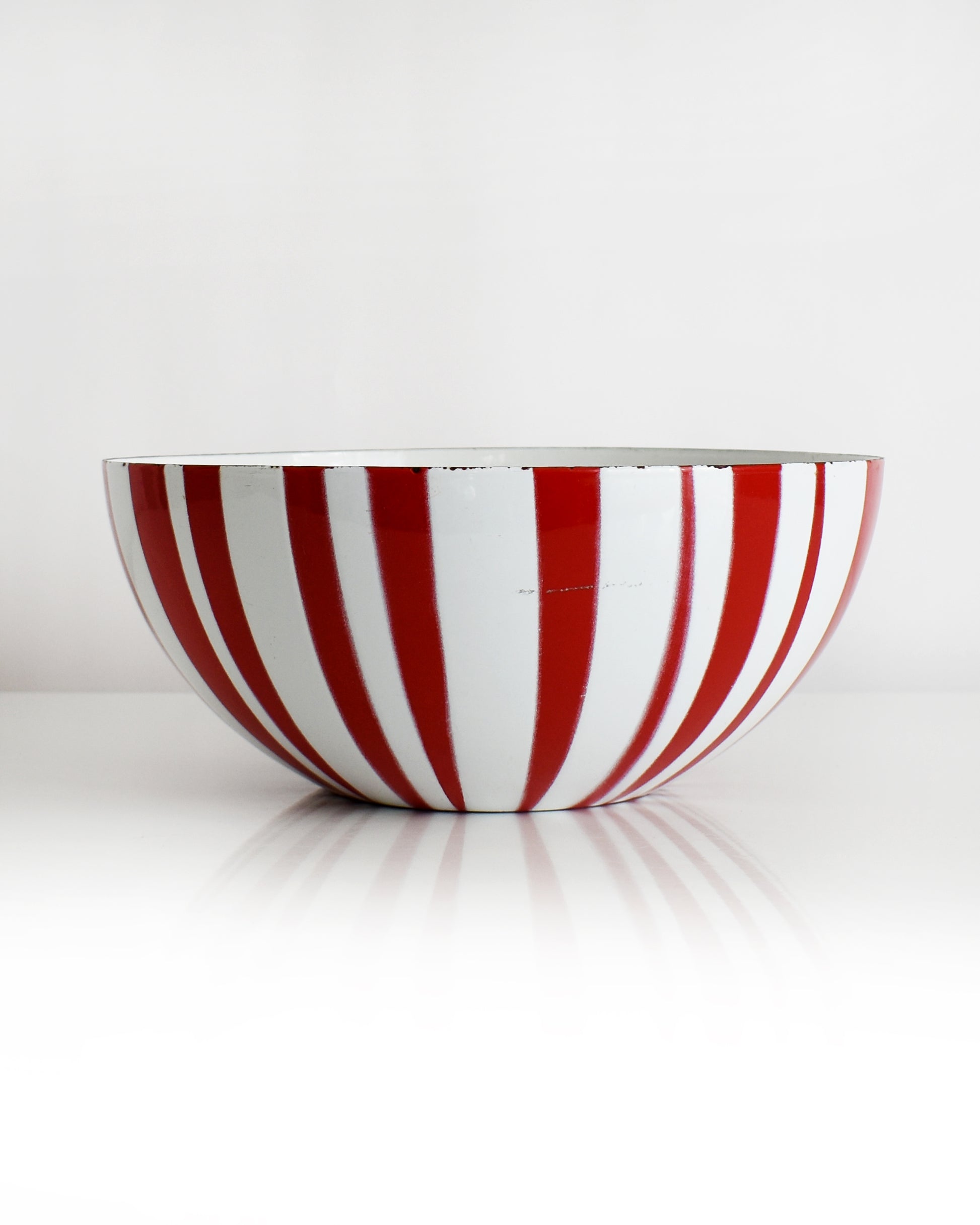 a vintage red and white striped Cathrineholm bowl on a white background