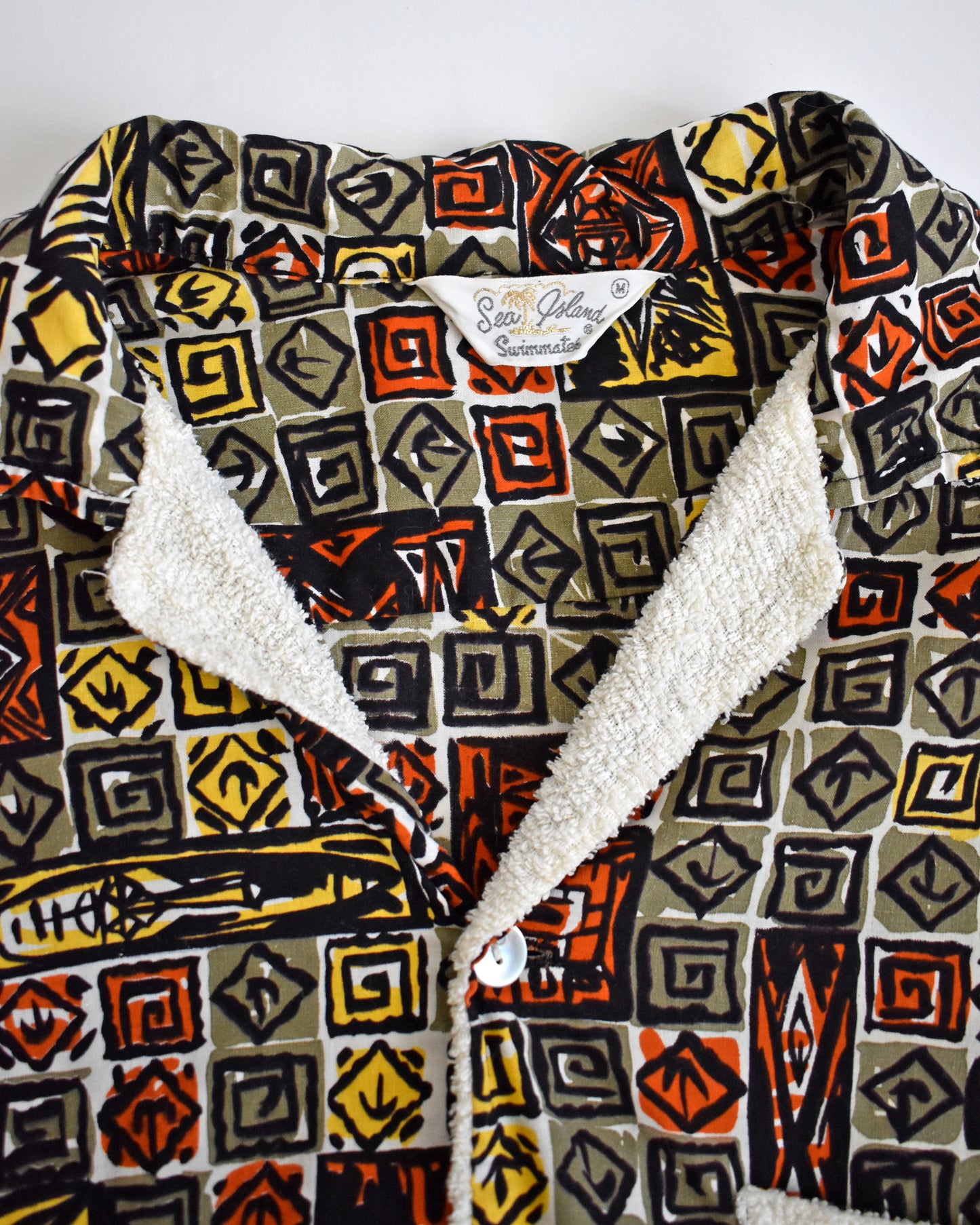 close up of the Sea Island Swimmates tag on a vintage 1960s short-sleeve cabana shirt with geometric pattern on a white background
