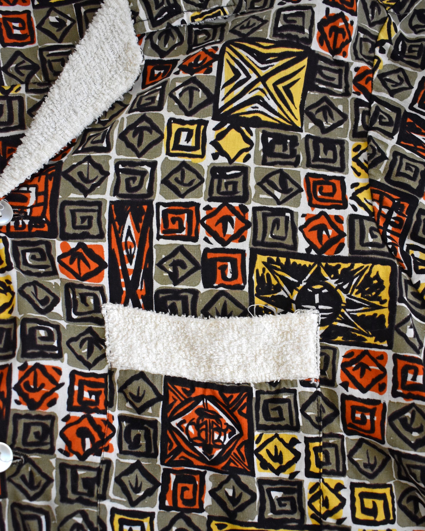 close up of the terry cloth trimmed pocket on a vintage 1960s short-sleeve cabana shirt with geometric pattern on a white background