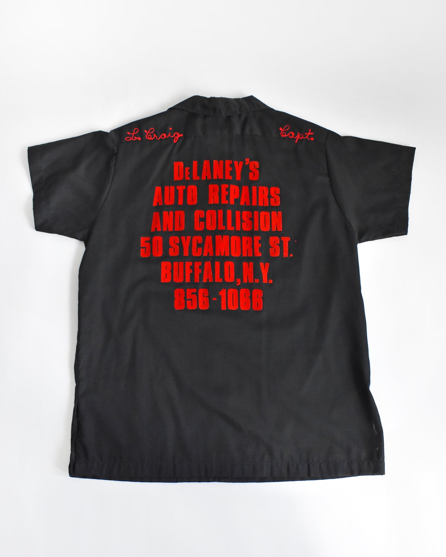 a vintage 1970s black bowling shirt with red lettering on a white background