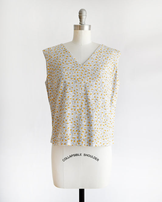 a vintage floral sleeveless top on a mannequin with 'Collapsible Shoulder' label against a white background