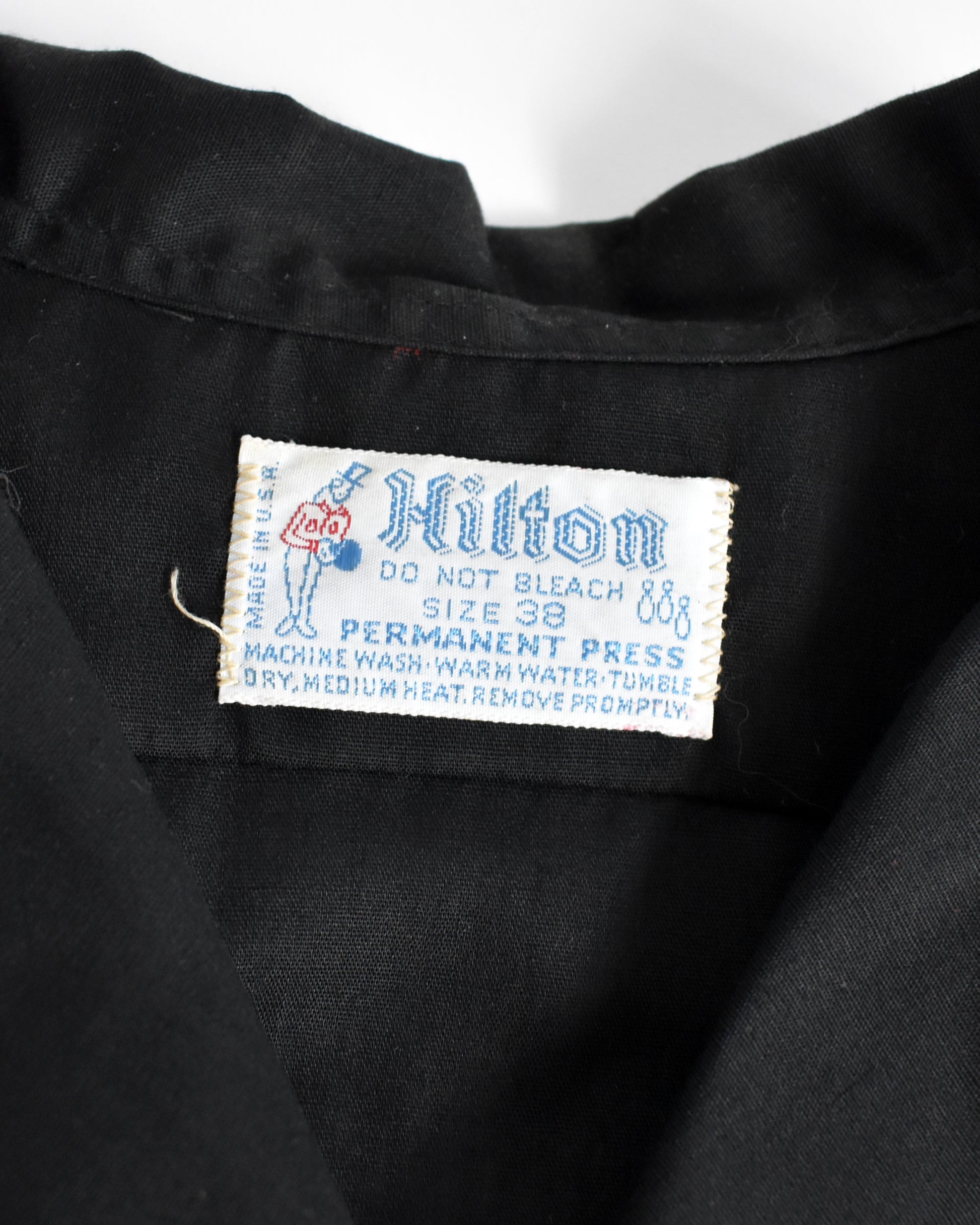 Label on a black garment with 'Hilton' branding and care instructions.