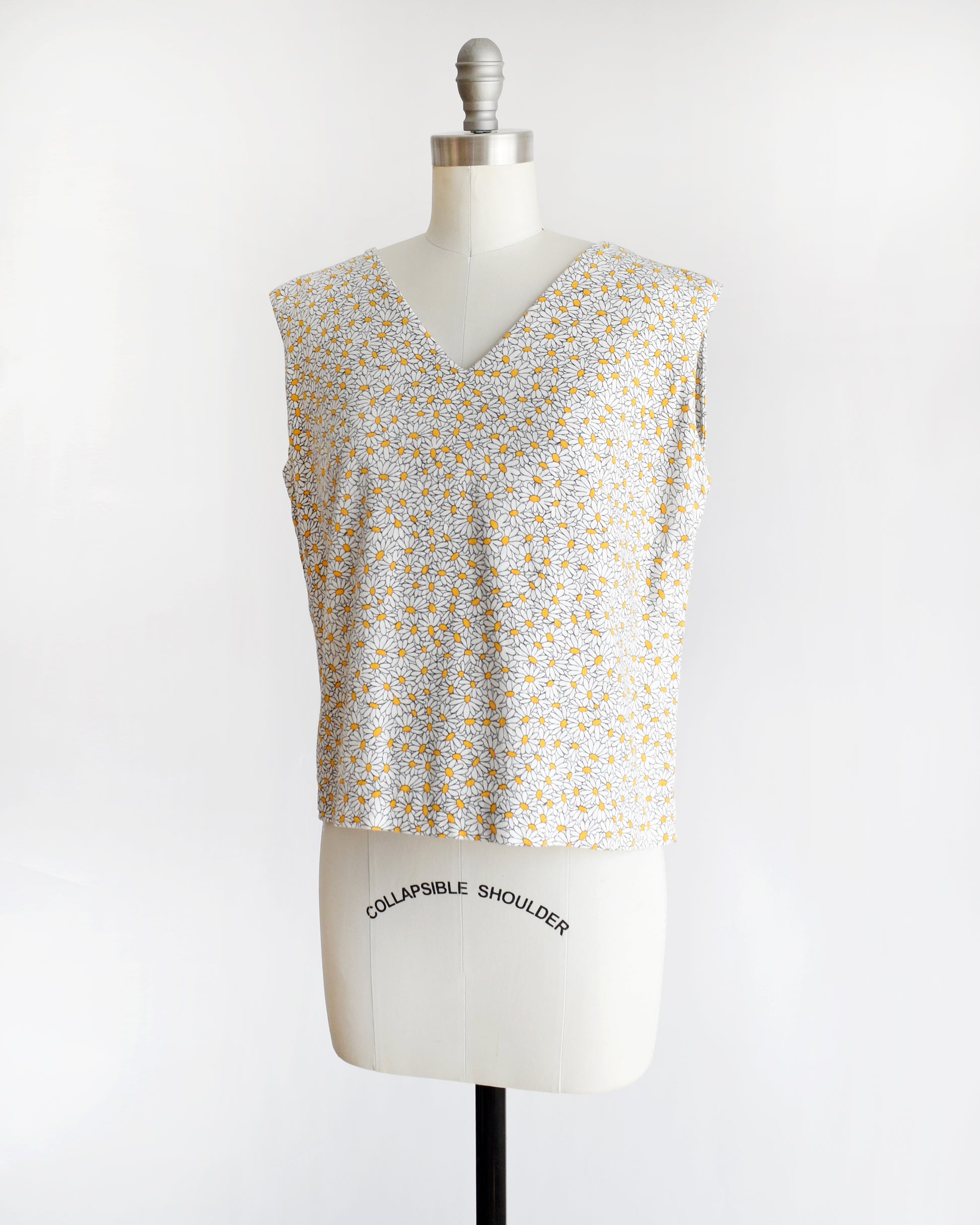 side front view of a vintage floral sleeveless top on a mannequin with 'Collapsible Shoulder' label against a white background