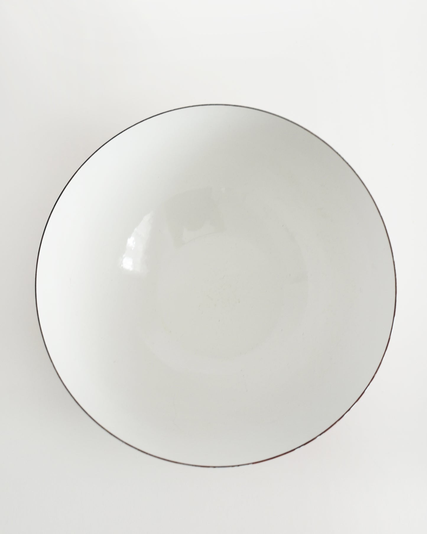 overhead shot of a vintage red and white striped Cathrineholm bowl on a white background