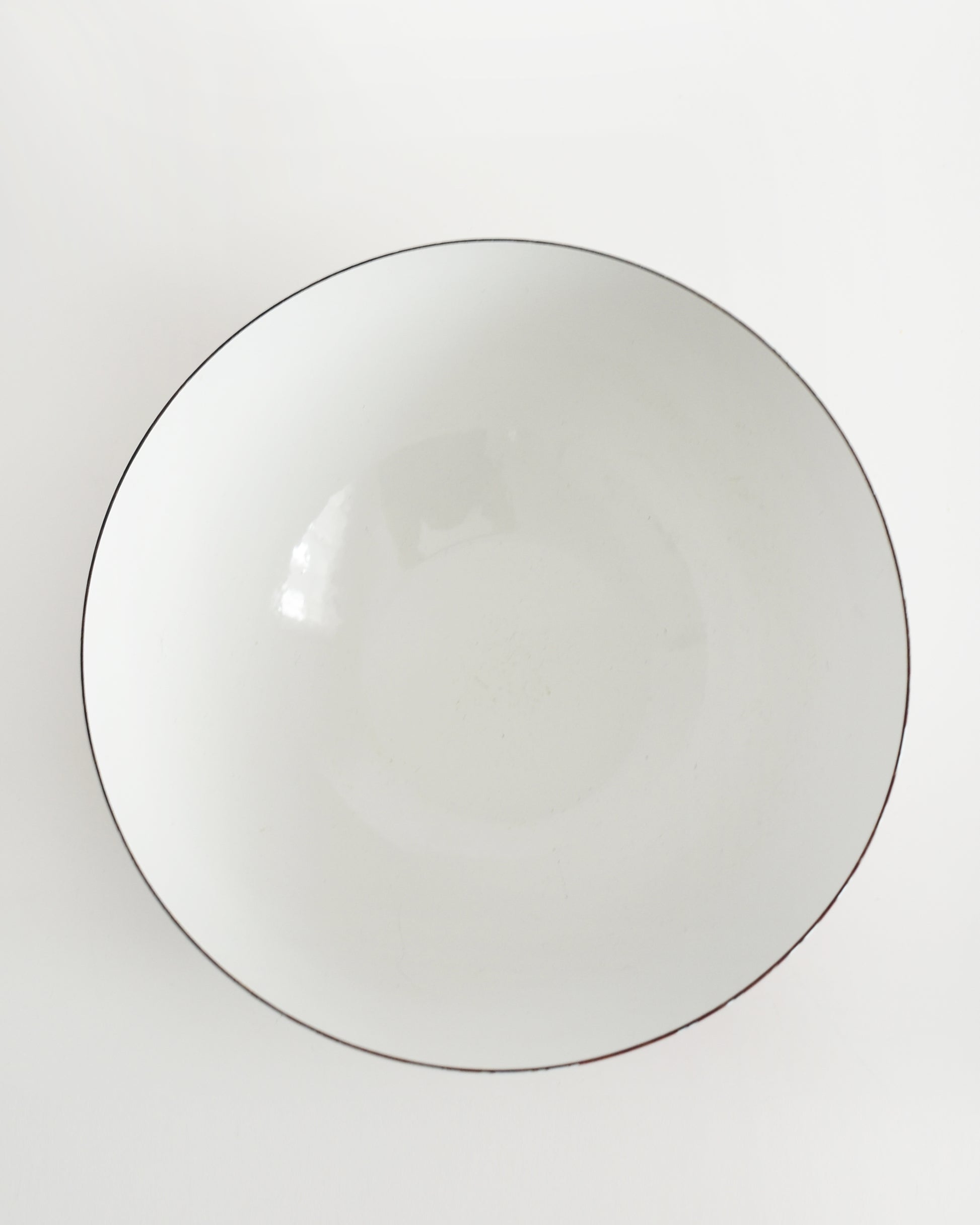 overhead shot of a vintage red and white striped Cathrineholm bowl on a white background