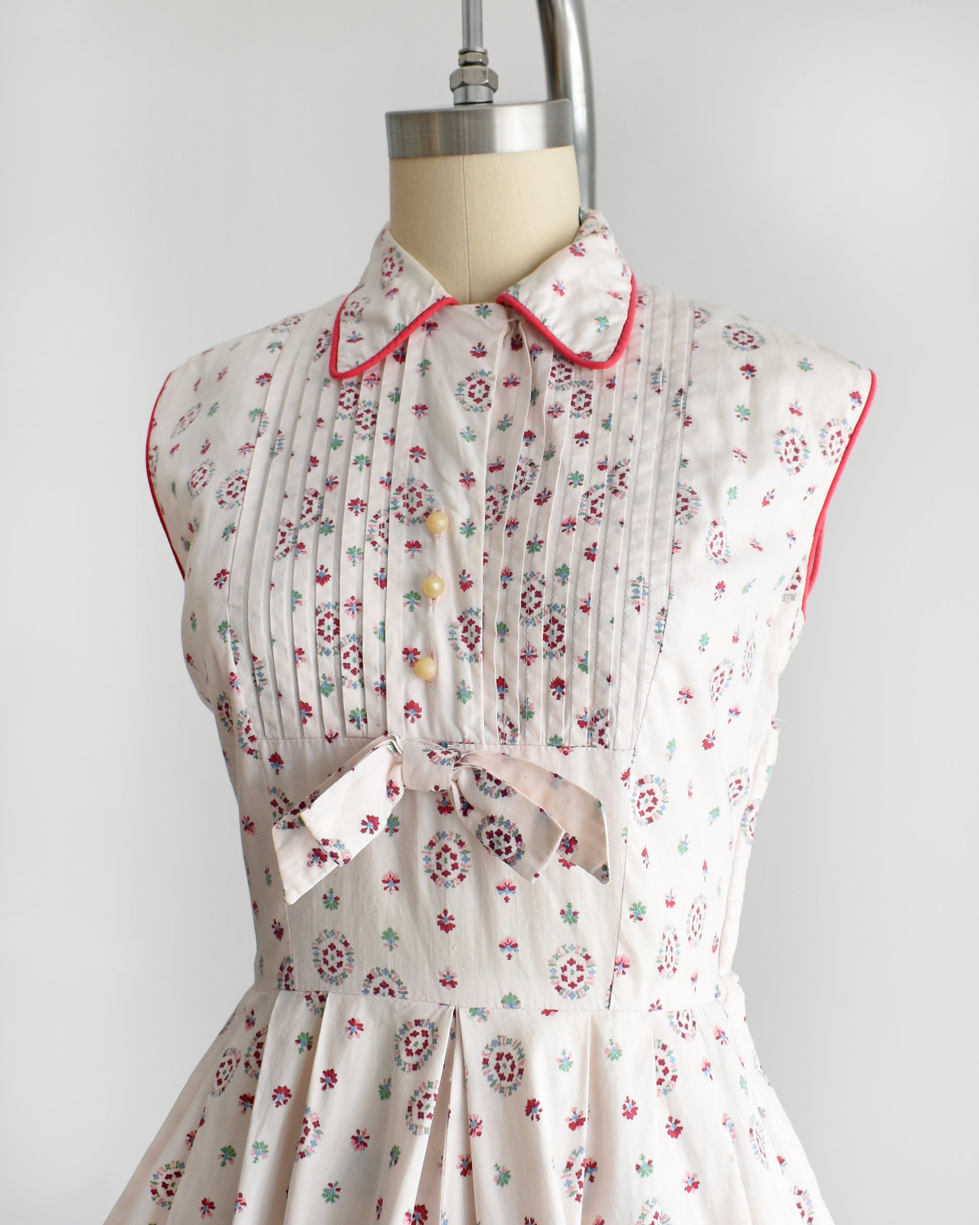 side front view of a vintage 1950s floral dress on a mannequin against a white background