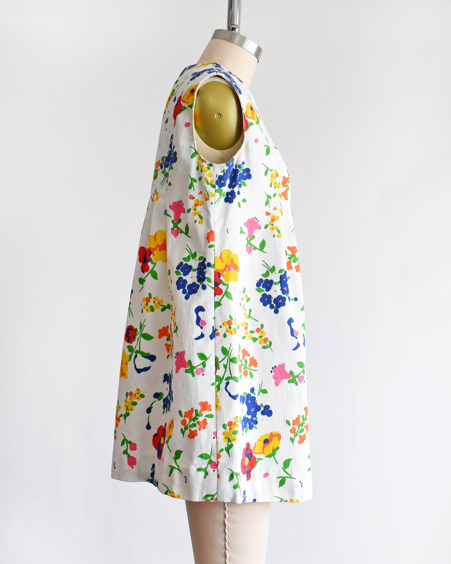 side view of a vintage 1960s floral dress on a mannequin against a white background