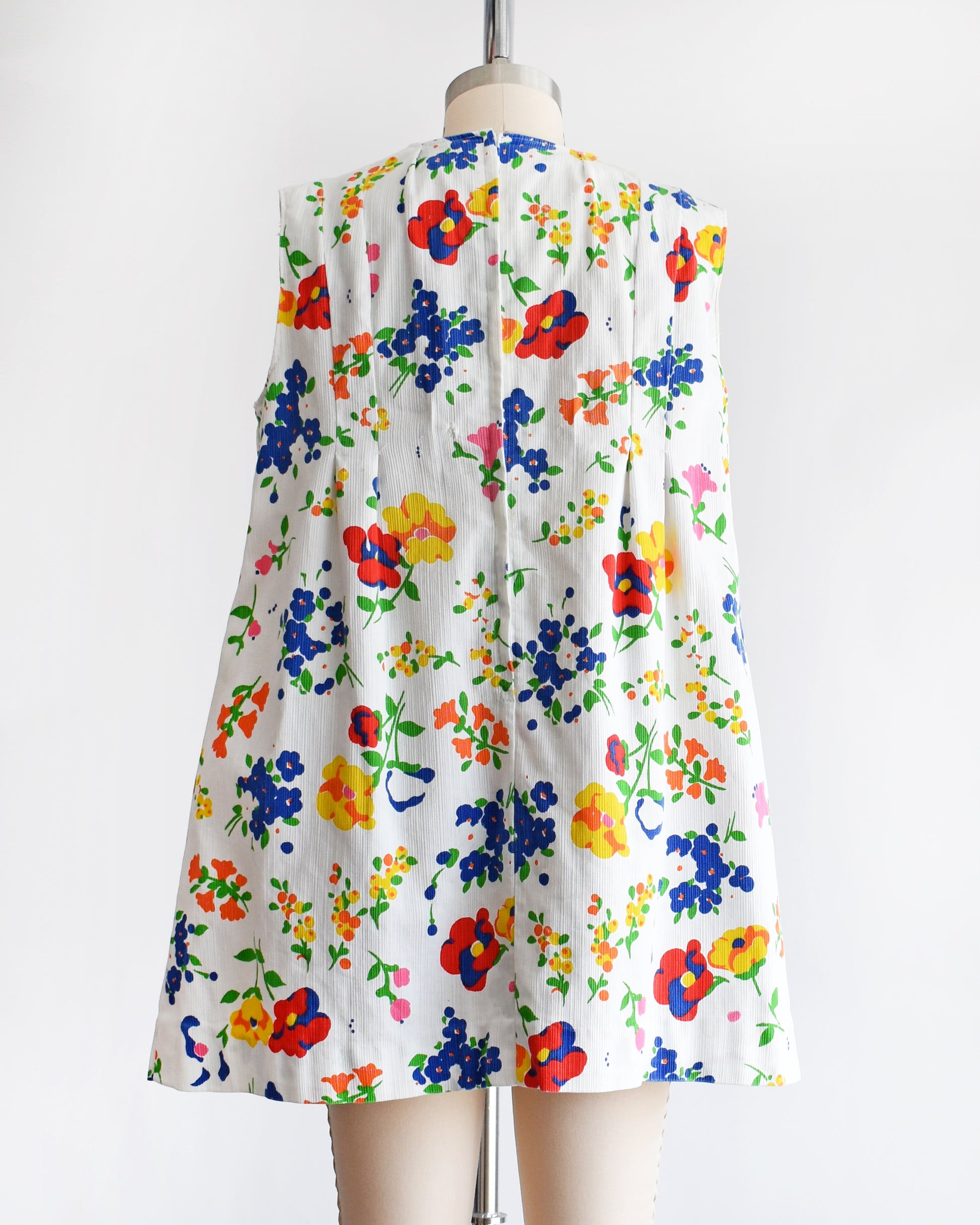 back view of a vintage 1960s floral dress on a mannequin against a white background