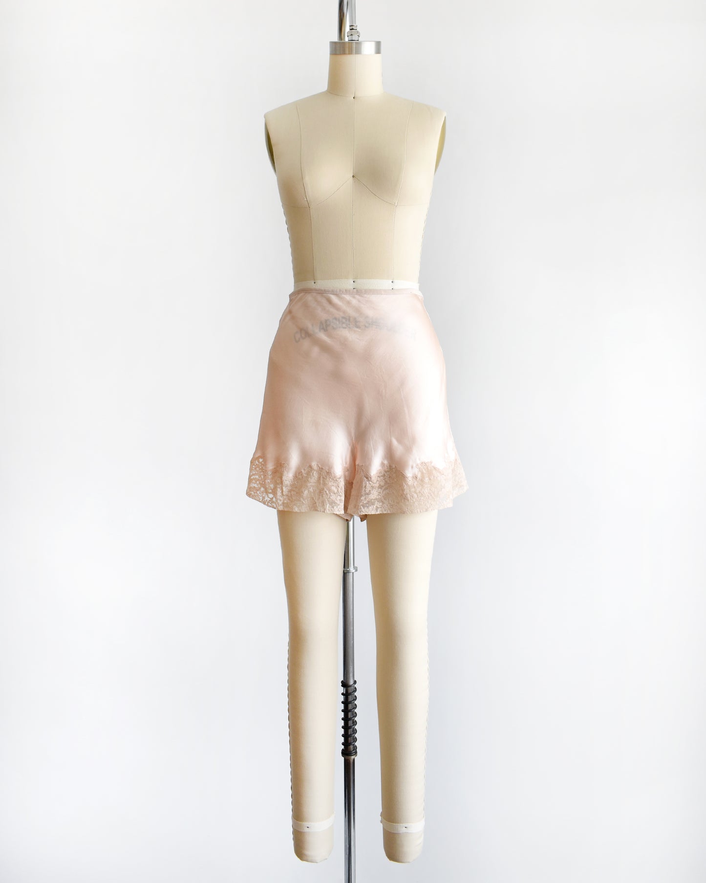 vintage 1940s light peach silk shorts with lace trim on a dress form