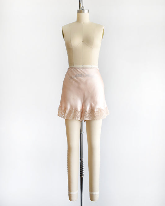 vintage 1940s light peach silk shorts with lace trim on a dress form
