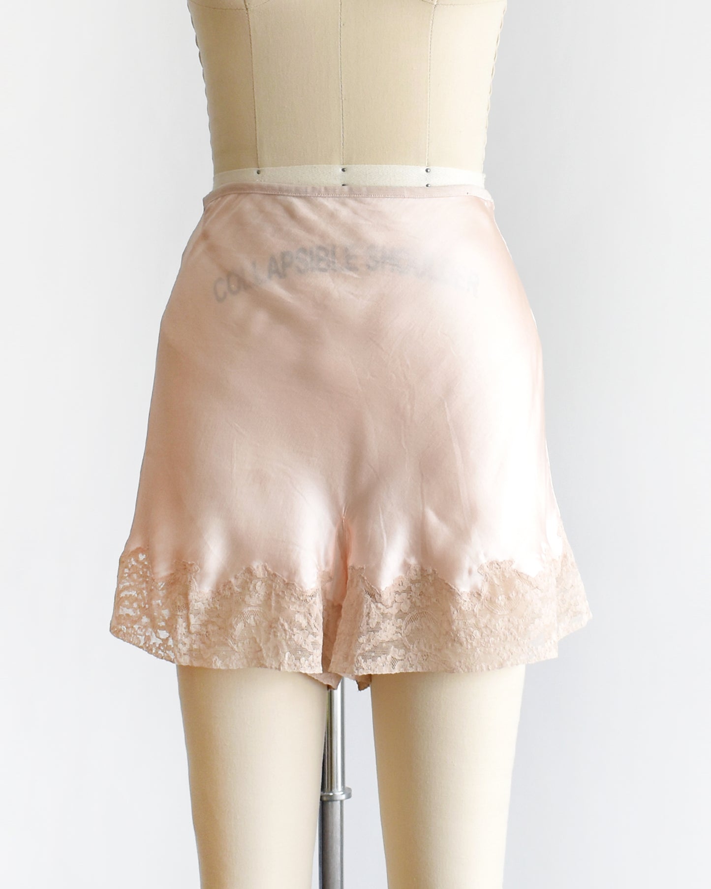 vintage 1940s light peach silk shorts with lace trim on a dress form