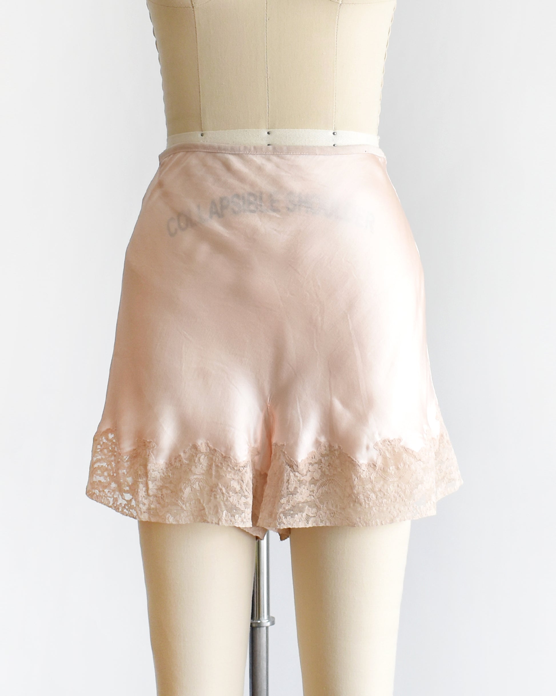 vintage 1940s light peach silk shorts with lace trim on a dress form