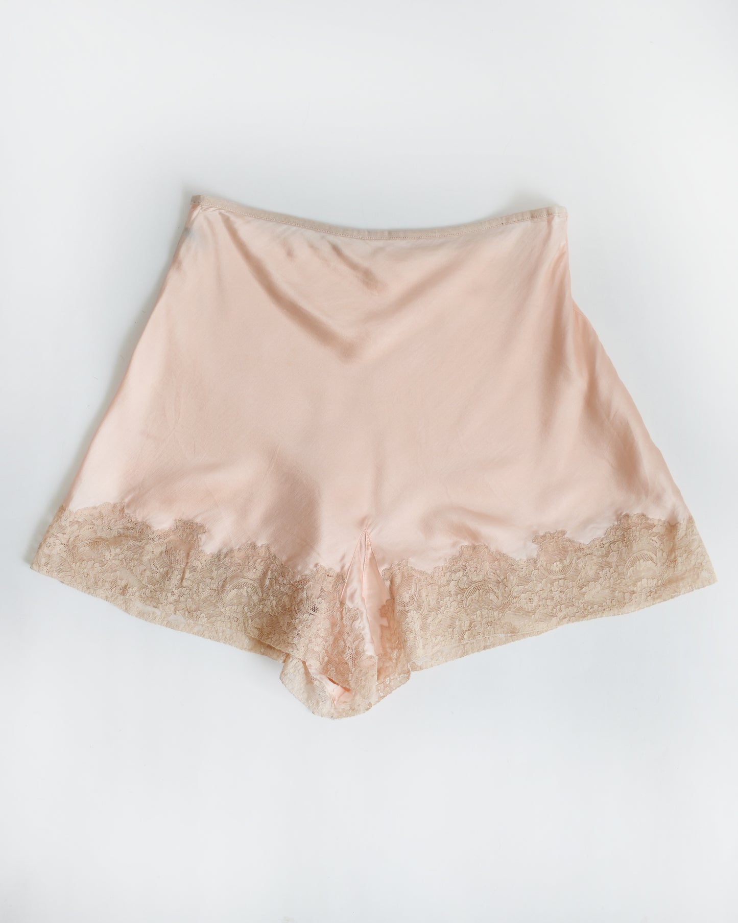 vintage 1940s light peach silk shorts with lace trim on a white background