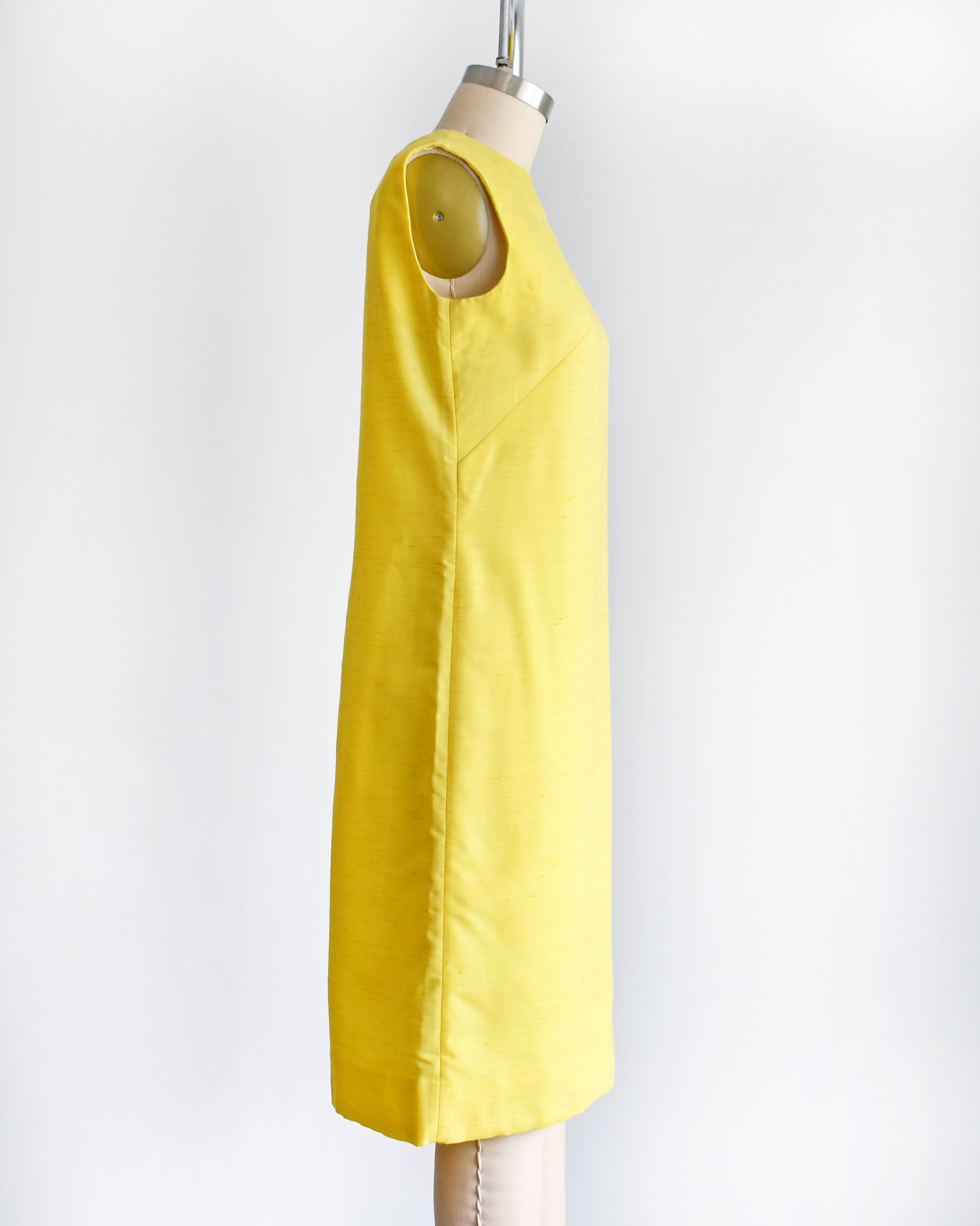 side view of a vintage 1960s yellow shift dress on a dress form