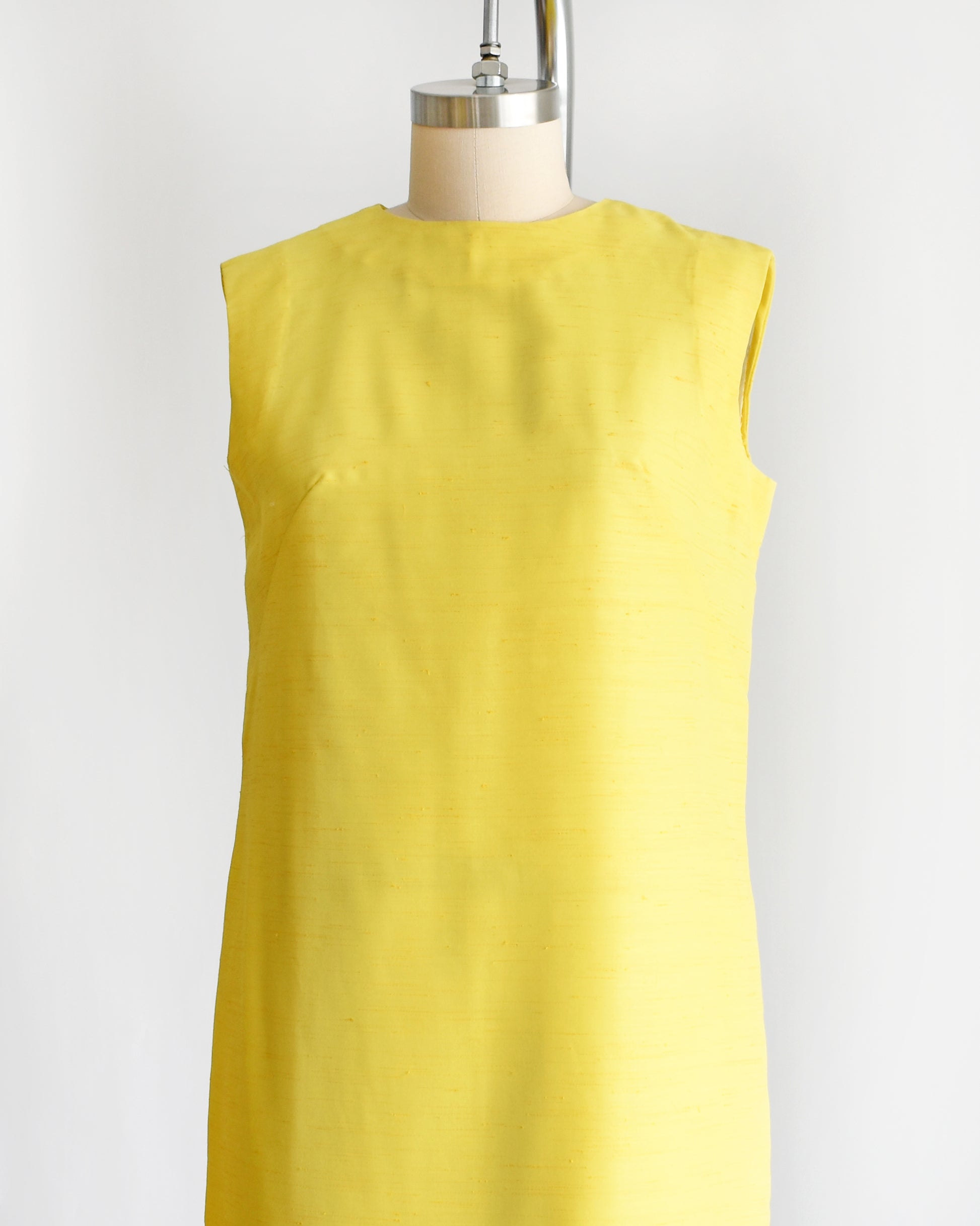 side front view of a vintage 1960s yellow shift dress on a dress form