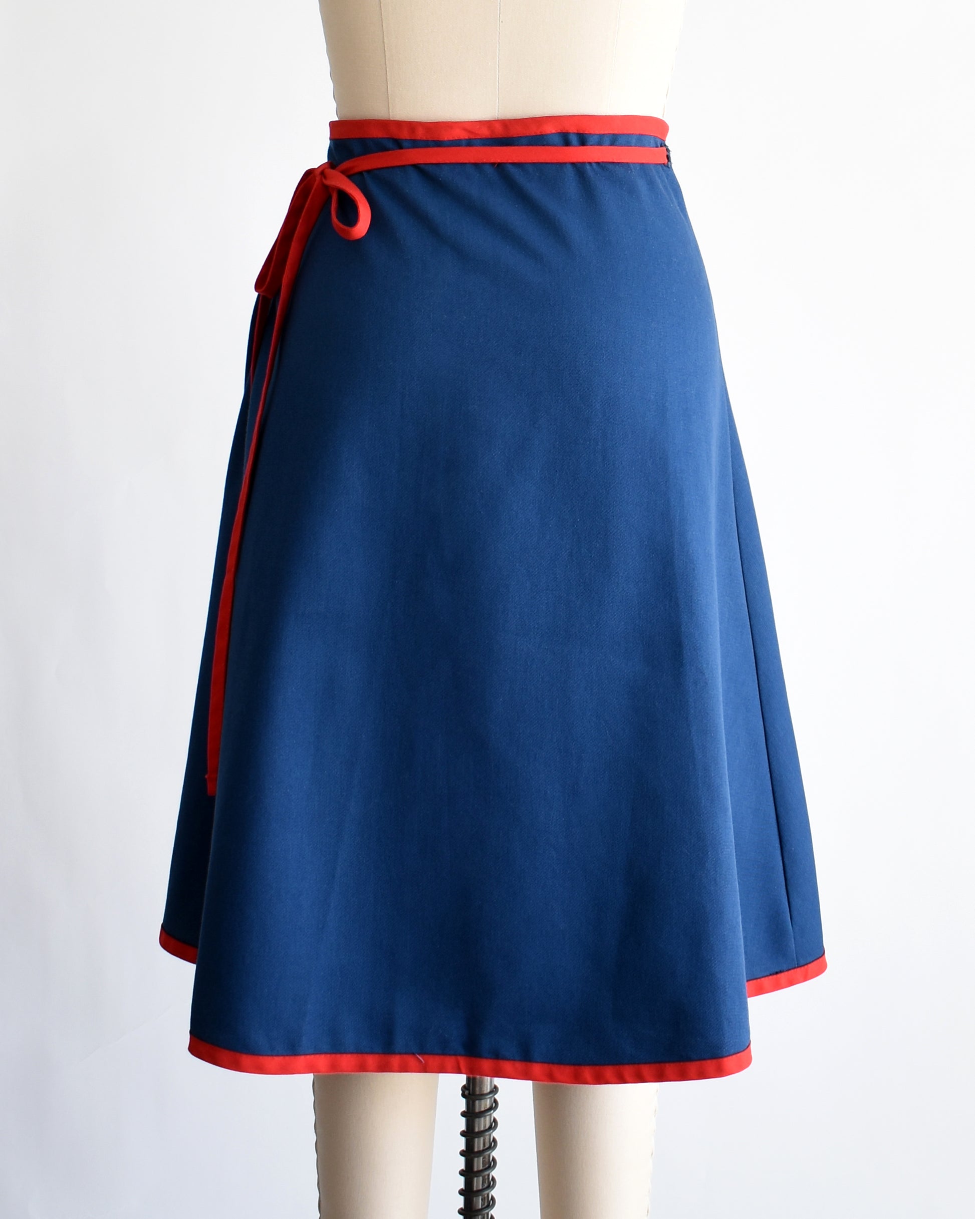back view of a vintage blue wrap skirt with a colorful sailboat design on a mannequin against a white background