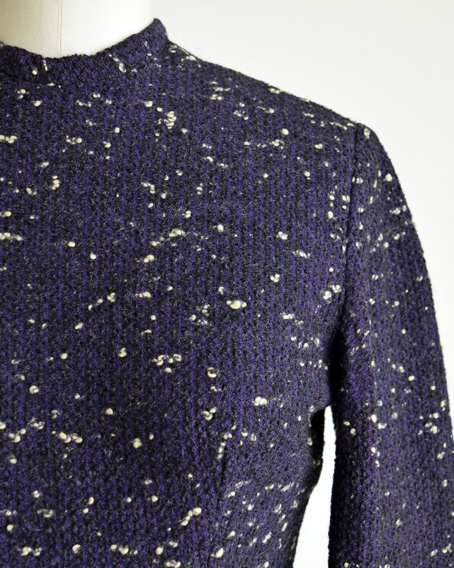 Close up of the black and purple wool with white flecked spots on a dress form.