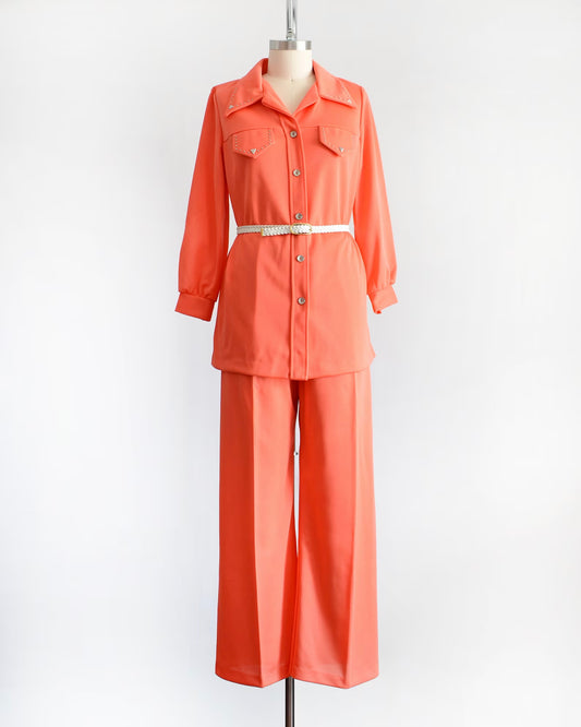vintage 70s orange matching blouse with silver studs with wide leg pants and white belt on a dress form