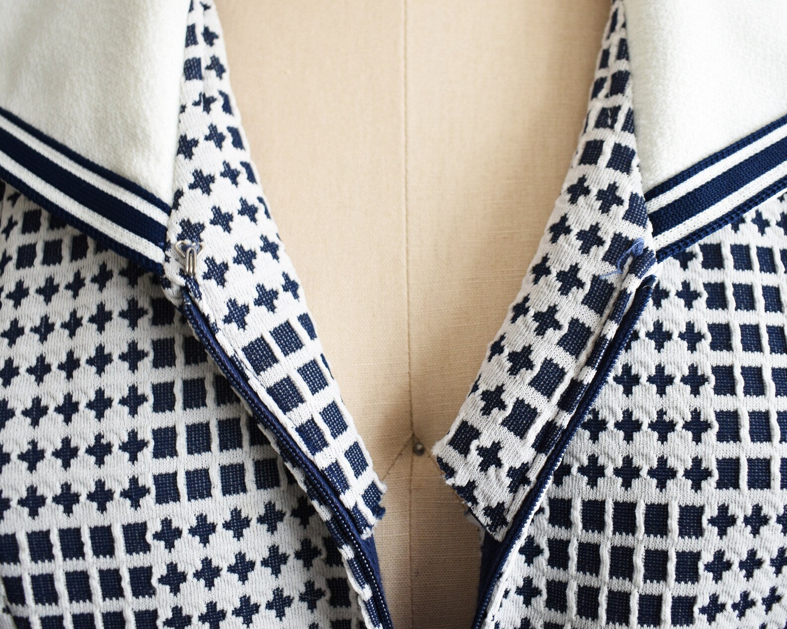 Close up of the navy geometric print, and the hook closure at the top of the zipper