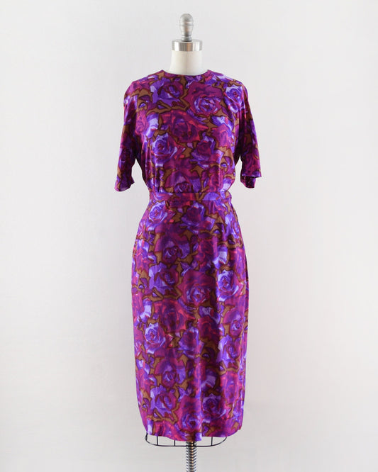 A vintage 1960s two piece top and skirt set in various shades of purple, along with bright pink, and light brown mid century floral print.