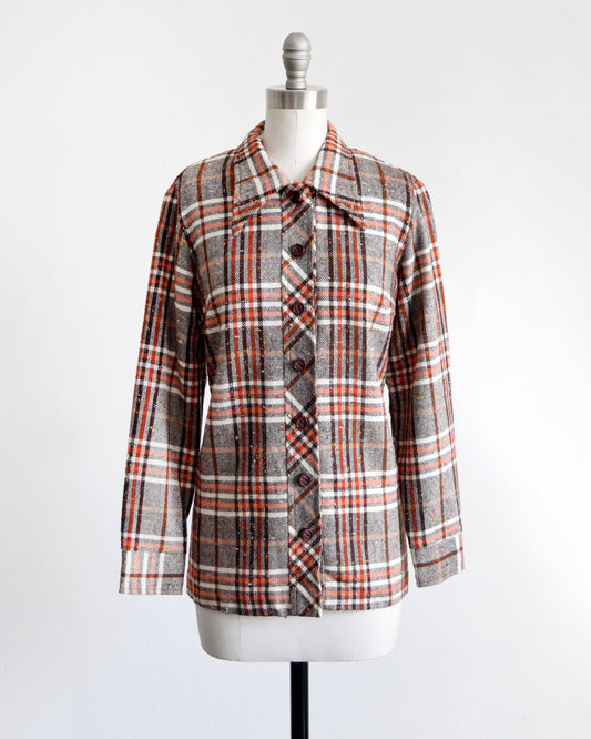 A vintage 70s brown, orange, and white plaid button up flannel shirt on a dress form