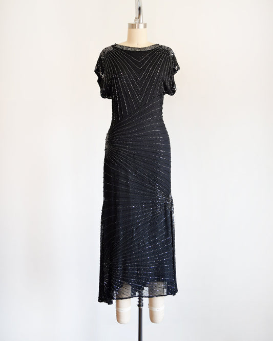 A vintage 80s/90s black silk dress that has silvery sequins and beading covering the dress is various lines.