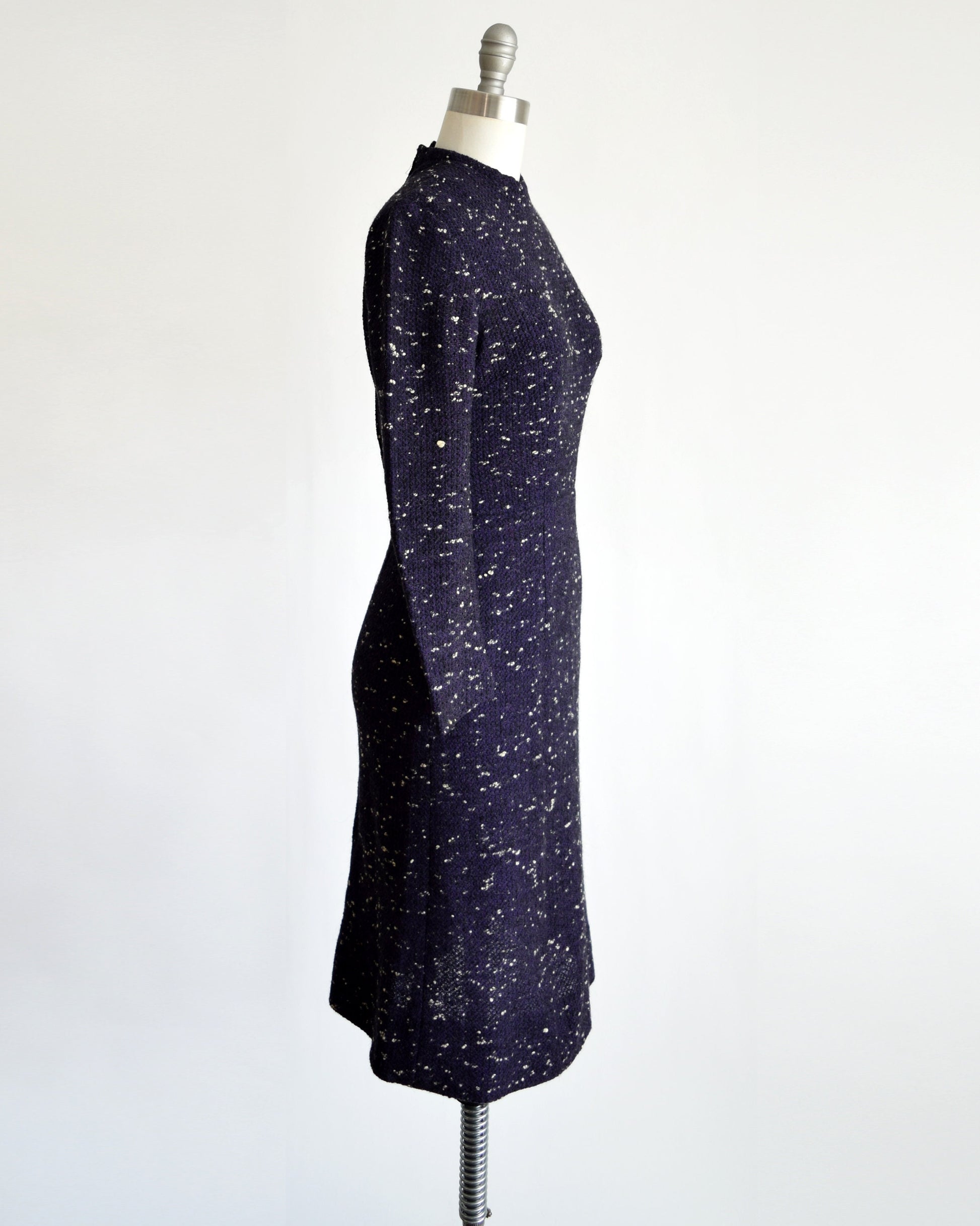 Side view of a vintage 50s dress that has black and purple wool with white flecked spots on a dress form.