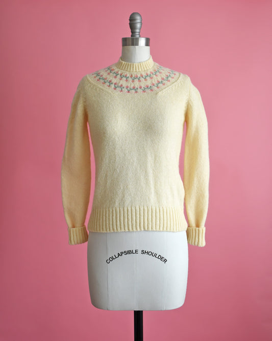 A vintage 80s cream sweater with pink and green flowers around the collar. 