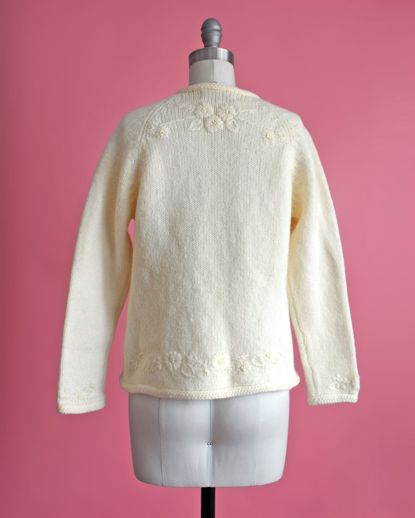 Back view of a vintage 60s cream cardigan with matching floral embroidery on the front. The sweater is on a dress form.