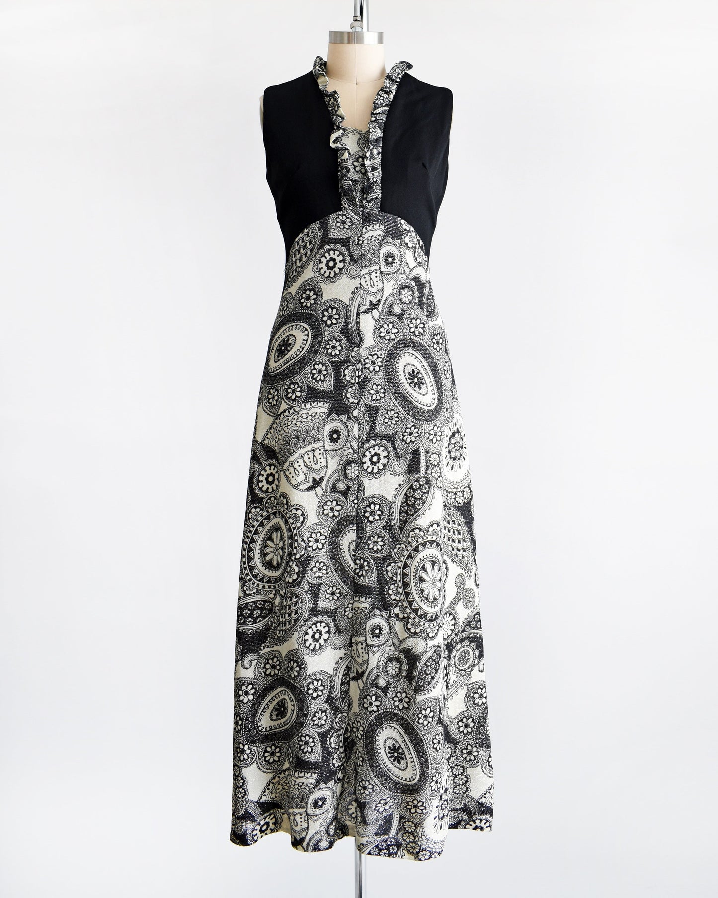 A vintage 70s black and white floral paisley print maxi dress on a dress form.