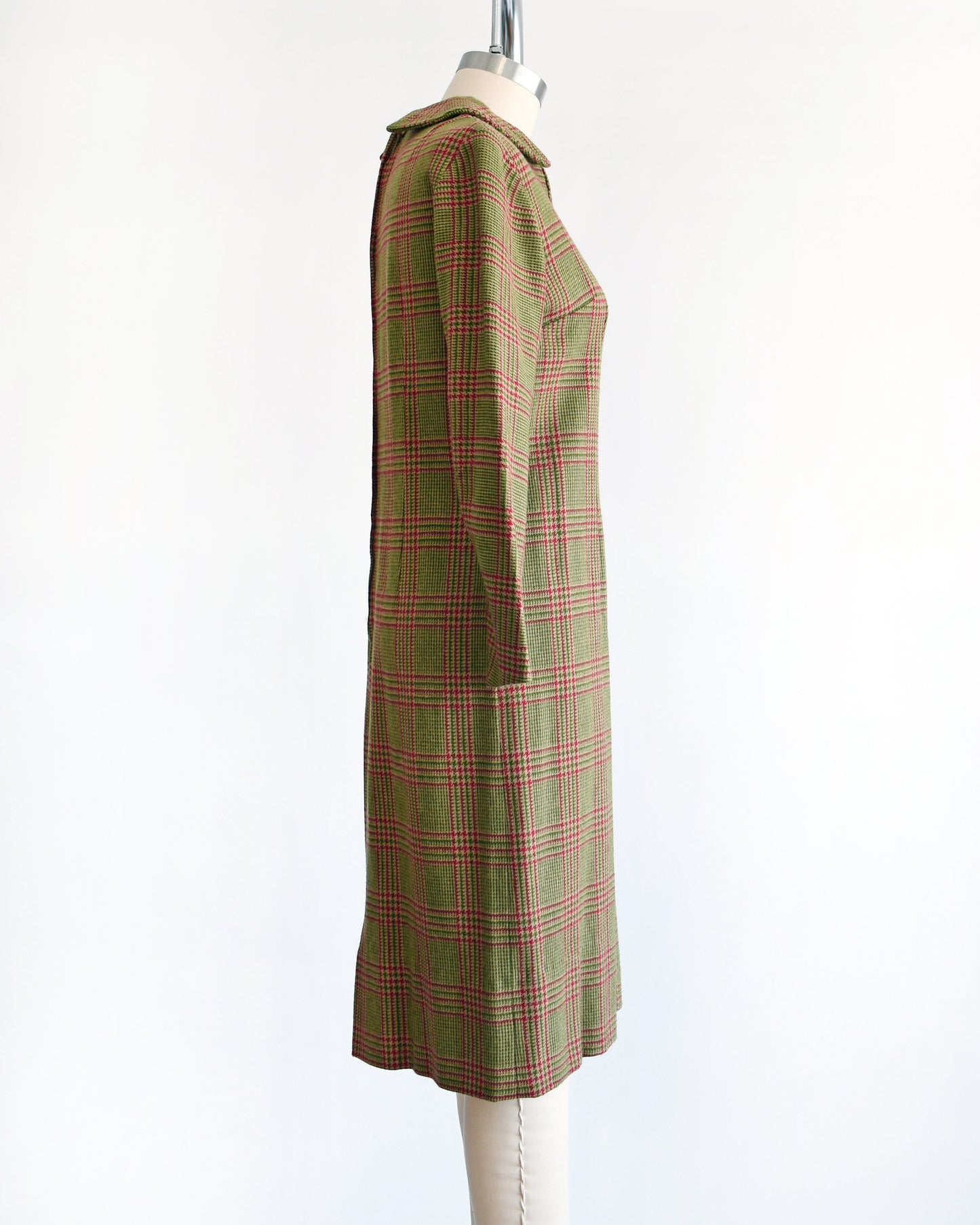 Side view of a vintage 60s green and pink plaid wool dress with Peter Pan style collar and long sleeves. The dress is modeled on a dress form.