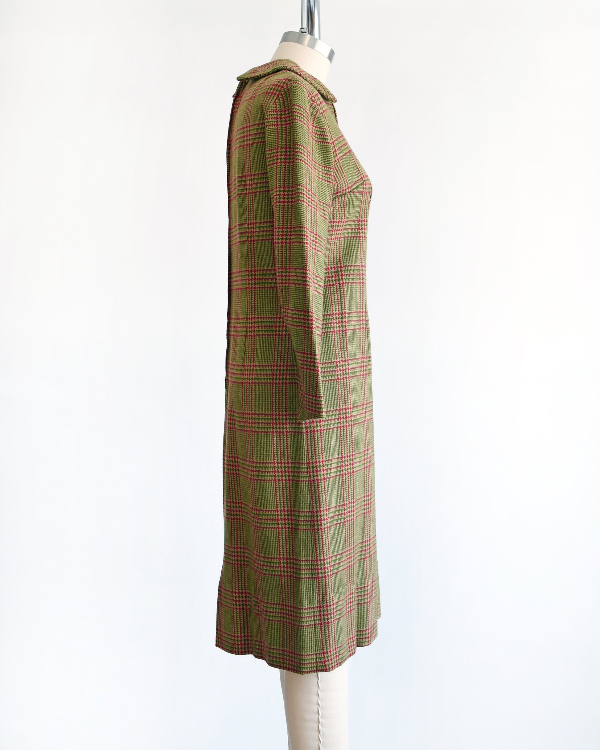 Side view of a vintage 60s green and pink plaid wool dress with Peter Pan style collar and long sleeves. The dress is modeled on a dress form.