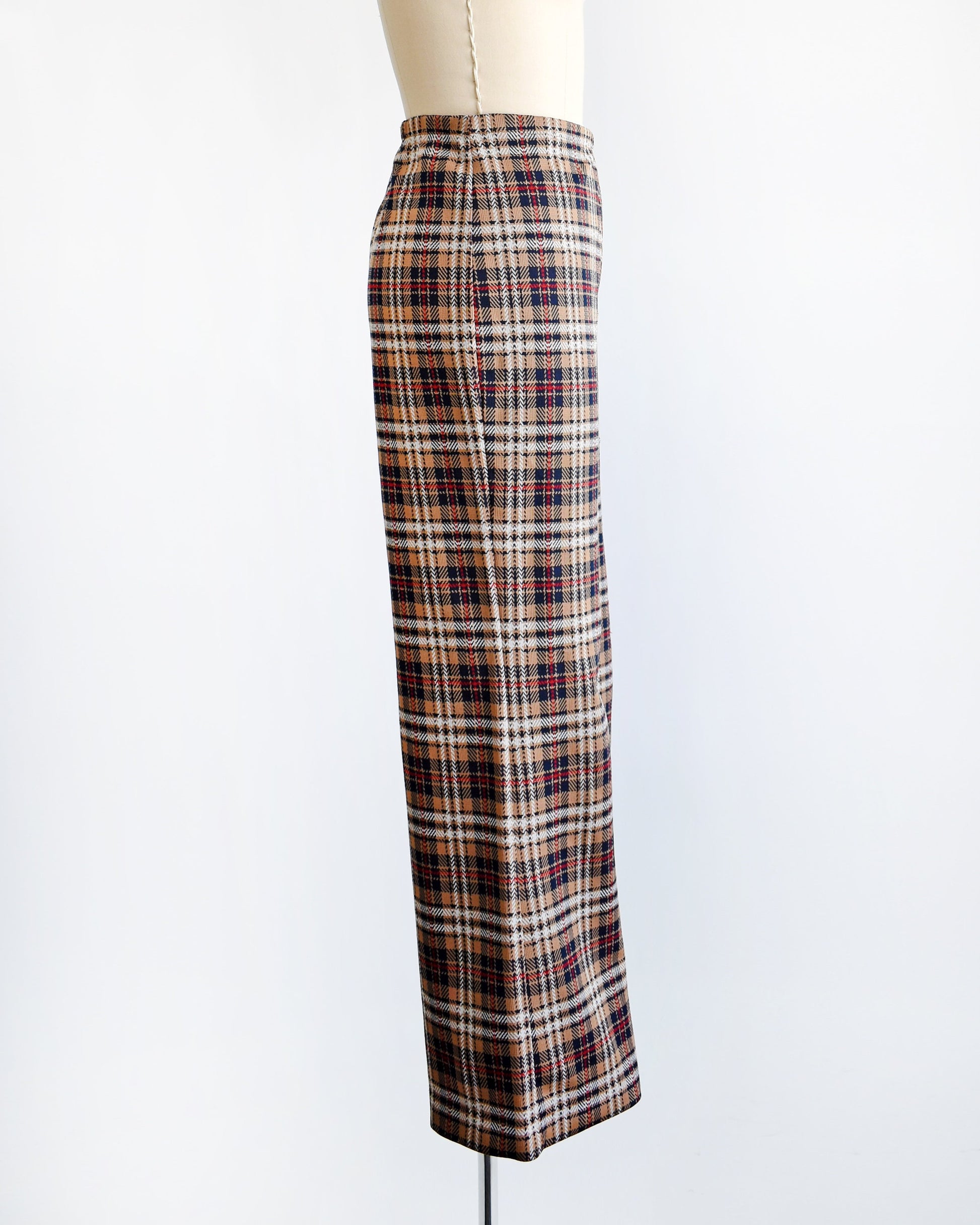 Side view of a pair of vintage 70s brown, blue, red, black, and white plaid pants with flared bottoms on a dress form.